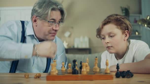 Aged man is teaching his grandson how to play chess - Video
