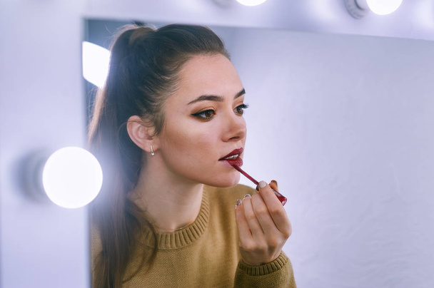 Una joven se maquilla mirándose en el espejo
 - Foto, imagen