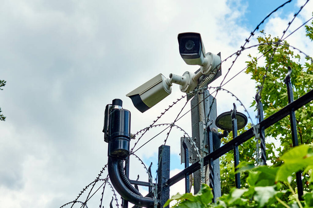 Cámara CCTV y detectores de movimiento en la valla con alambre bardeado
 - Foto, Imagen