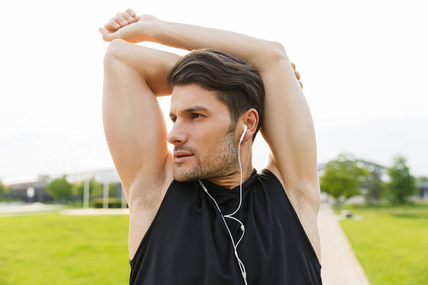 Image of attractive man working out with earphones and running a - Foto, immagini