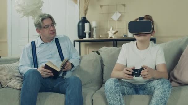 A boy is playing in VR-glasses while his granddad is looking at him - Materiaali, video