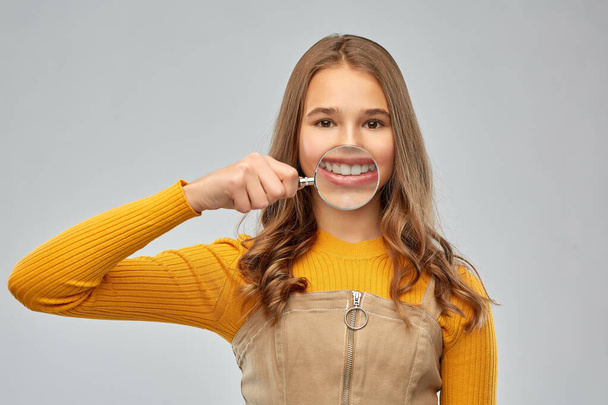 teenage girl shows teeth through magnifying glass - Foto, Imagen