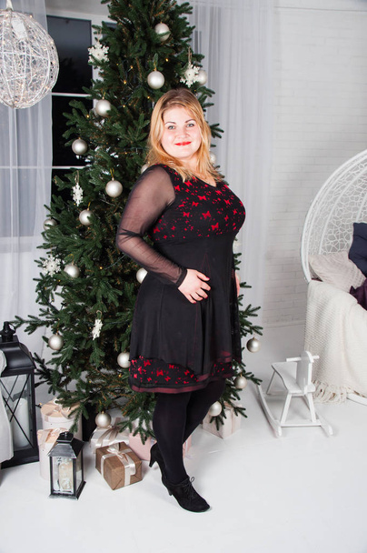 Lush, beautiful, young woman near Christmas tree with gifts - Fotoğraf, Görsel