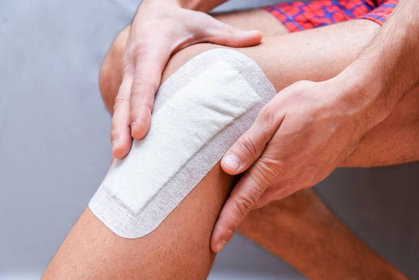medical plaster is glued to the knee of the male leg after surgery - Φωτογραφία, εικόνα