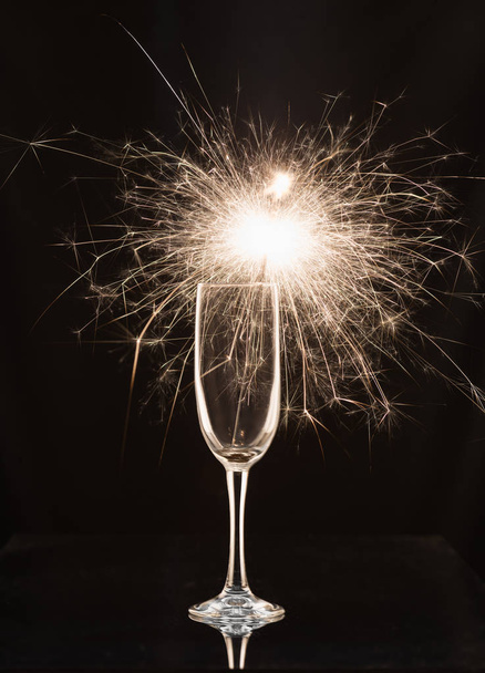 Champagne glass with lit sparkler against a dark background - Photo, Image