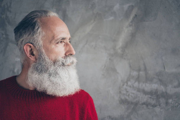 Closeup photo of nice aged guy looking side empty space minded wear red knitted pullover jumper cool hipster santa outfit isolated grey color concrete wall background - Fotó, kép