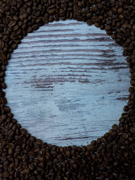 γκρο πλαν ξύλινου τραπεζιού του οποίου τα τεμάχια είναι φρεσκοψημένοι καφέ αρωματικοί κόκκοι καφέ - Φωτογραφία, εικόνα