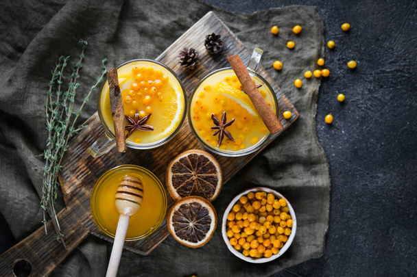 Tengeri homoktövis tea narancs, fahéj, méz és fűszerek sötét háttér felső nézet másolás hely. - Fotó, kép