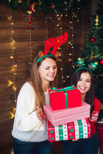 Two caucasian beautiful woman holding gift boxes on Christmas background. - Foto, afbeelding