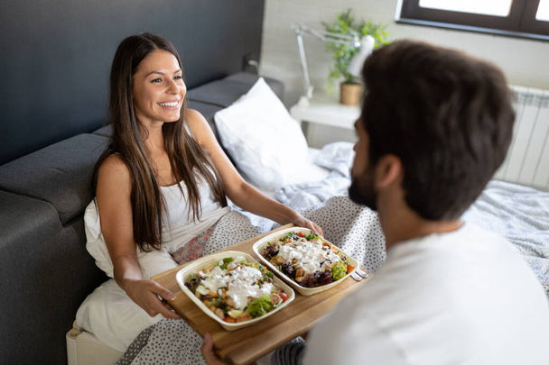 Romantic happy young couple having breakfast in bed - Fotó, kép