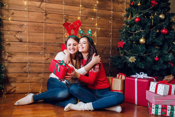Two beautiful young women giving a christmas present each other - Фото, зображення