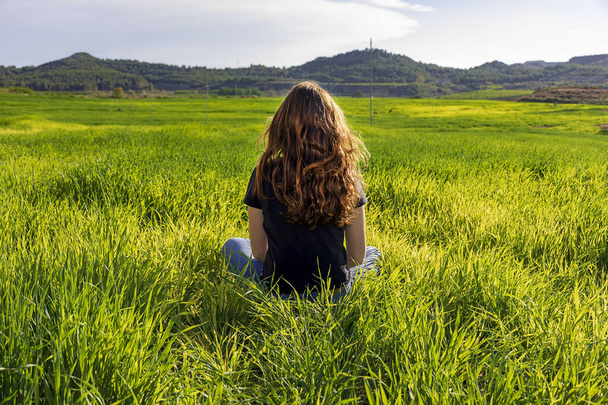 Młoda biała ruda kobieta, z długimi włosami i piegami, siedząca na trawie w pozycji do jogi. uważność, medytacja i relaksująca scena - Zdjęcie, obraz