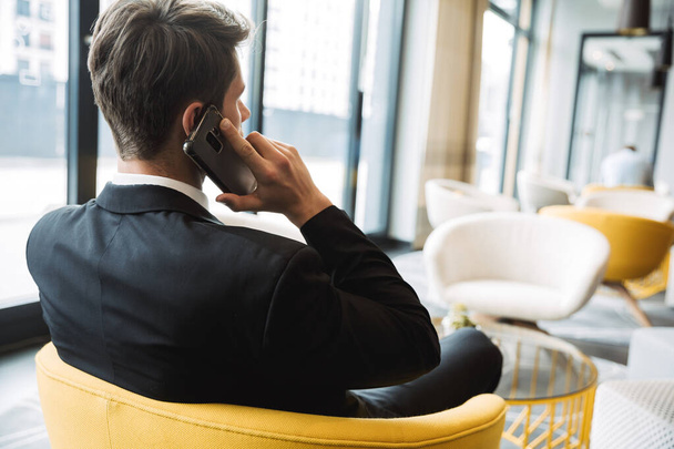 Fénykép magabiztos fiatal üzletember beszél okostelefonon, miközben - Fotó, kép