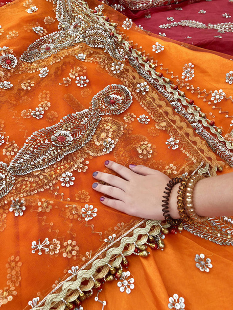 Female hand touches indian fabric of orange color. - Photo, Image