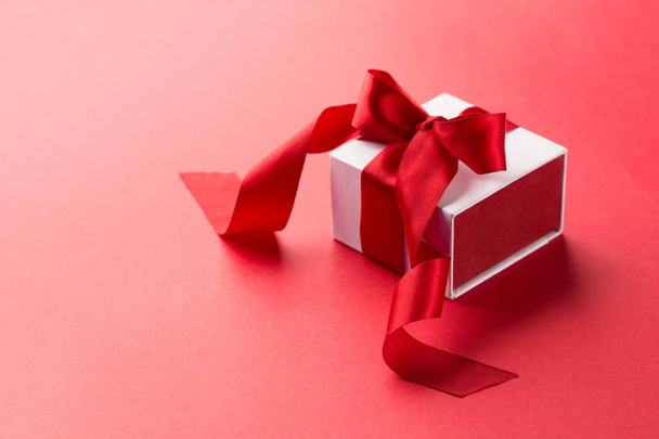 White Gift box with red ribbon on red background - Φωτογραφία, εικόνα