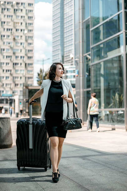business travel business woman. Stylish girl with a suitcase in the big city. Business Vacation. Business trip. Warsaw - Foto, afbeelding