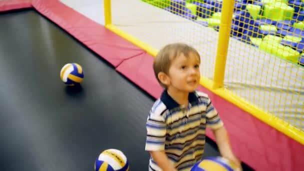 4k video of little boy throwing balls in basketball ring on trampoline at children playground in shopping mall - Footage, Video