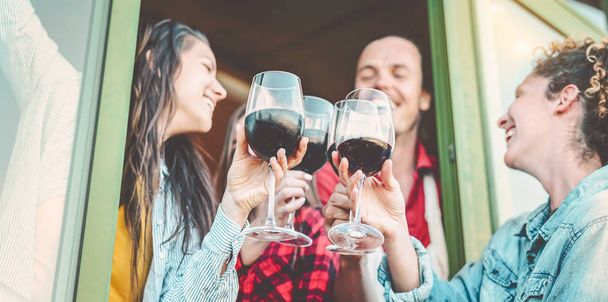 赤ワインを屋外で楽しむ幸せな友人-農家でワイングラスを応援し、飲む若者のグループ-若者文化のライフスタイルと友情の概念 - 写真・画像