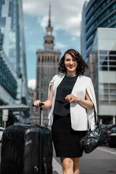 ビジネス旅行ビジネスウーマン。大都会でスーツケースを持つスタイリッシュな女の子。ビジネスバケーション。出張だワルシャワ - 写真・画像