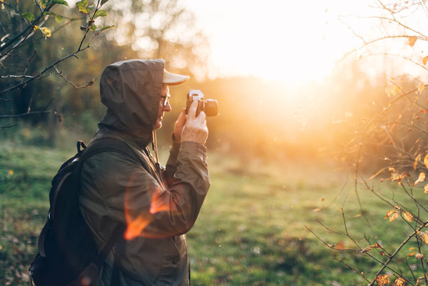 Old man taking photo in nature. Mature man taking pictures of the forest in fall. - Foto, Bild