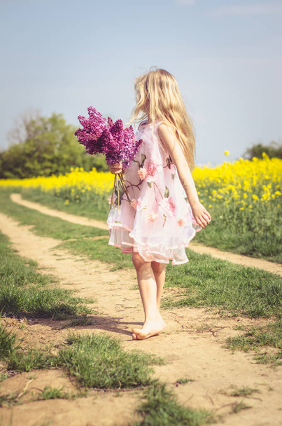 encantador niño caucásico con ramo de lila en las manos - Foto, imagen