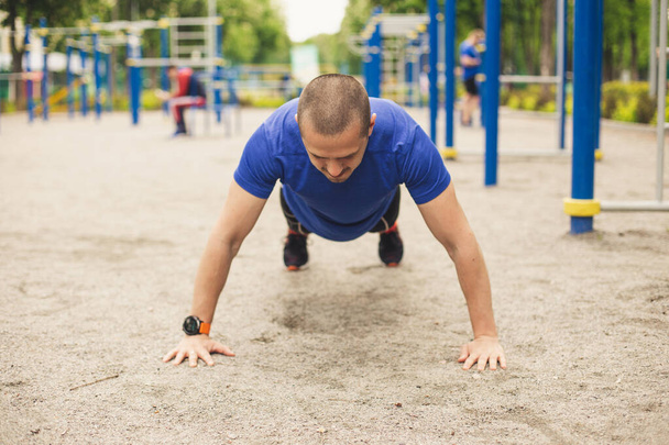 Man doing push ups at sports ground - Photo, Image