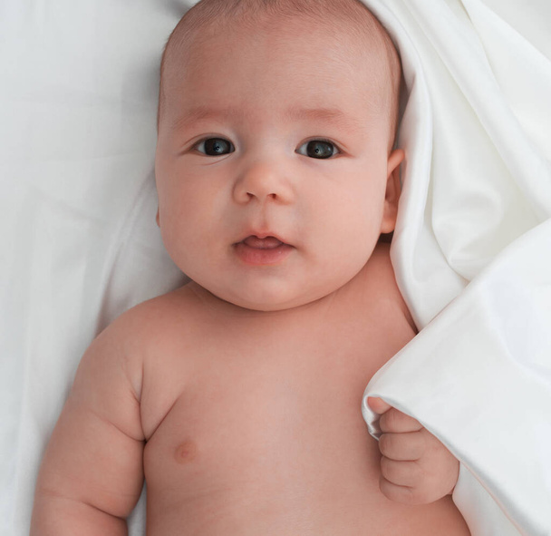 Baby boy lying on white linen close up studio shot - Φωτογραφία, εικόνα