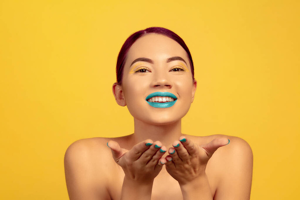 Portrait of beautiful young woman with bright make-up isolated on yellow studio background - Фото, зображення