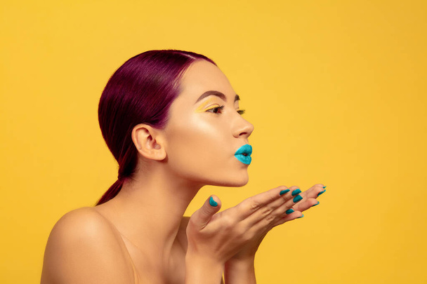 Portrait of beautiful young woman with bright make-up isolated on yellow studio background - Photo, Image