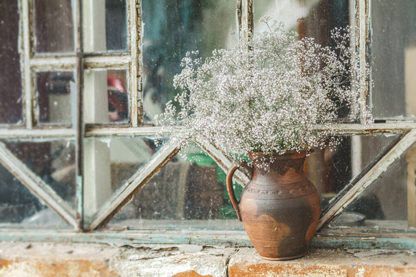 Beautiful retro still life with wild flowers in clay jug on wind - Photo, image