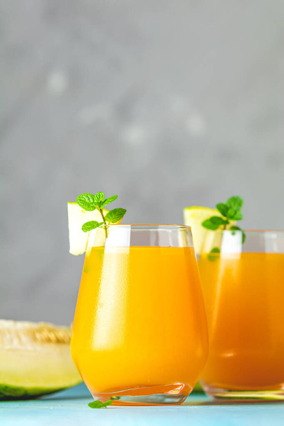 Yellow orange cocktail with melon and mint in glass on blue conc - Photo, Image