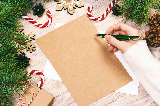 Famale hand writing a Christmas letter on wooden background. Toned - Photo, Image