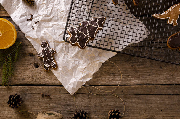 Homemade gingerbread in various shapes on an white paper on old wooden background. - Photo, Image
