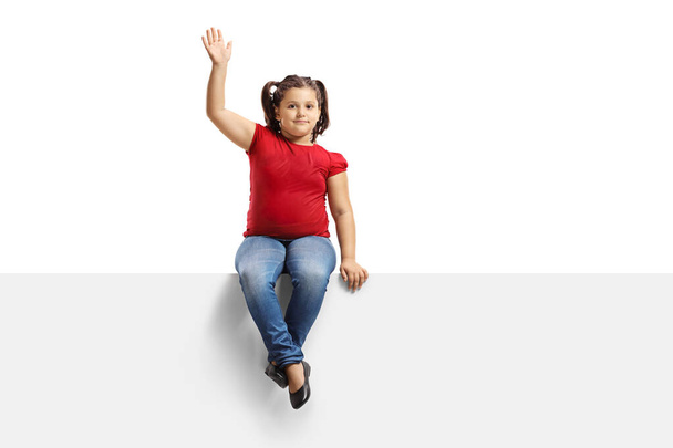 Criança feminina em uma camiseta vermelha em um painel acenando com a mão
  - Foto, Imagem