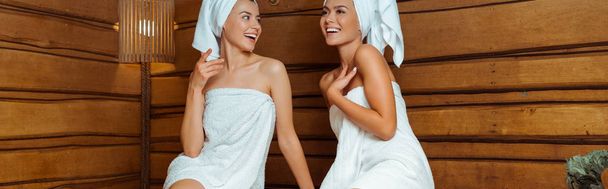 colpo panoramico di amici sorridenti e attraenti in asciugamani in sauna
  - Foto, immagini