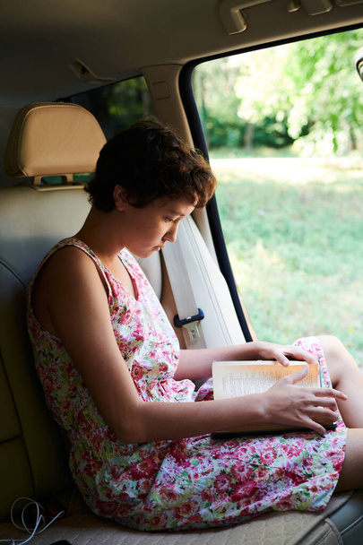 begeistertes Mädchen liest Buch im Auto auf Reise - Foto, Bild