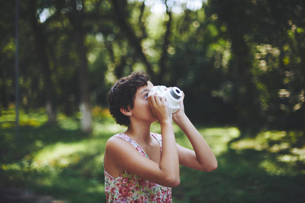 Aktywna dziewczyna robi zdjęcia na aparat w słonecznym lesie - Zdjęcie, obraz