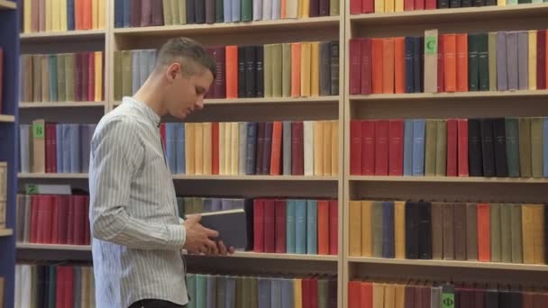 Een man selecteert een boek in de bibliotheek - Video
