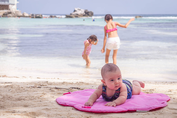 Bébé sur la plage couché sur le tapis rose sable
 - Photo, image