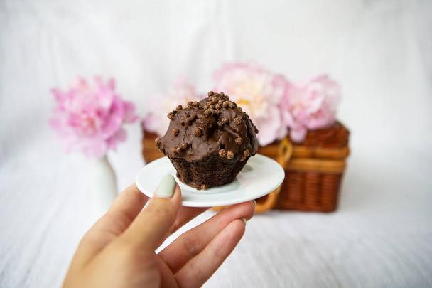 Chocolate muffins and beautiful pink peonies lie on a wooden suitcase. - Foto, afbeelding