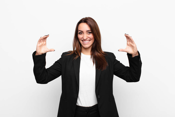 young pretty businesswoman framing or outlining own smile with both hands, looking positive and happy, wellness concept against white wall - Fotoğraf, Görsel