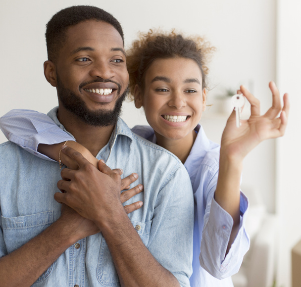glückliches schwarzes Paar umarmt Schlüsselanhänger im neuen Zuhause - Foto, Bild