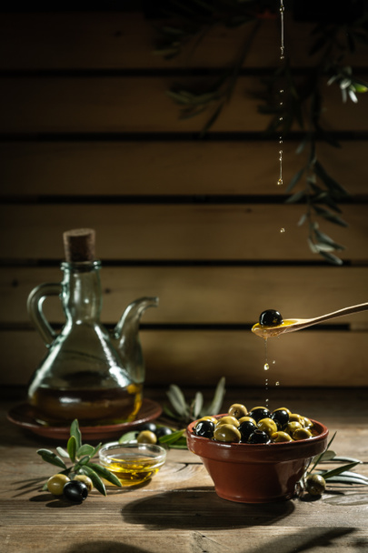 ελαιόλαδο και κλαδί ελιάς στο ξύλινο τραπέζι  - Φωτογραφία, εικόνα