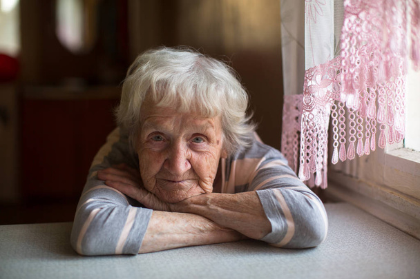 Detailní záběr portrét staré ženy u stolu doma. - Fotografie, Obrázek