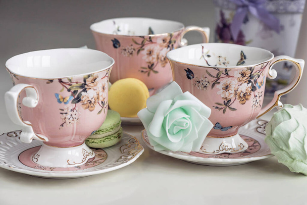 Tasses à thé rose avec ornement floral et bonbons macarons
 - Photo, image
