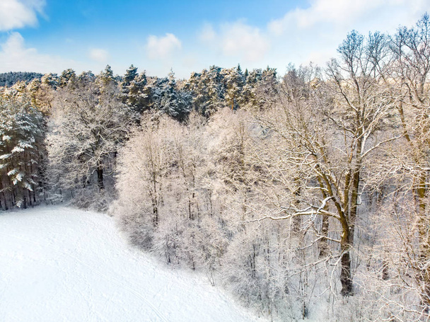 Beautiful aerial view of snow covered pine forests. Rime ice and hoar frost covering trees. Scenic winter landscape in Vilnius, Lithuania. - Foto, Bild