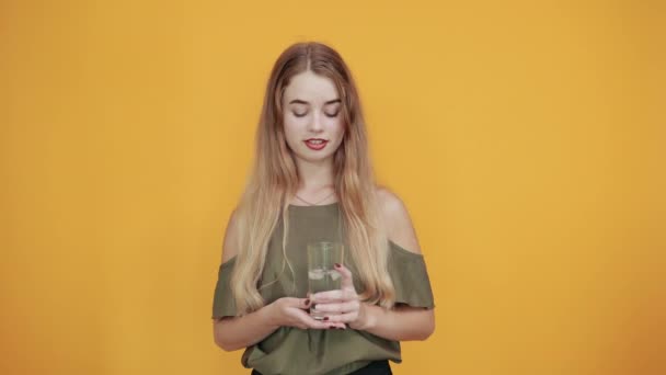 Young blonde woman girl in casual clothes keeping glass of water - Filmati, video