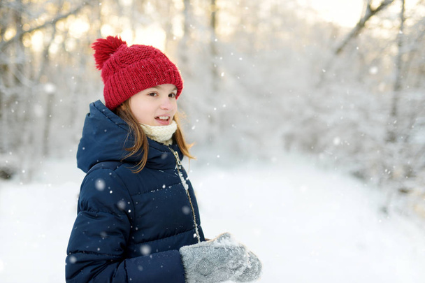 Adorable young girl having fun in beautiful winter park. Cute child playing in a snow. Winter activities for family with kids. - Fotó, kép