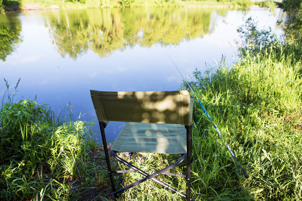 Armchair for fishing on the lake. Fishing rod in the water - Foto, Imagen