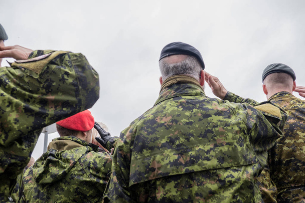 A kanadai katonák állnak és nézik a felvonulást. A hadsereg álcázza magát. Harcos ruhák. Ősz. Ez egy csúnya nap.. - Fotó, kép